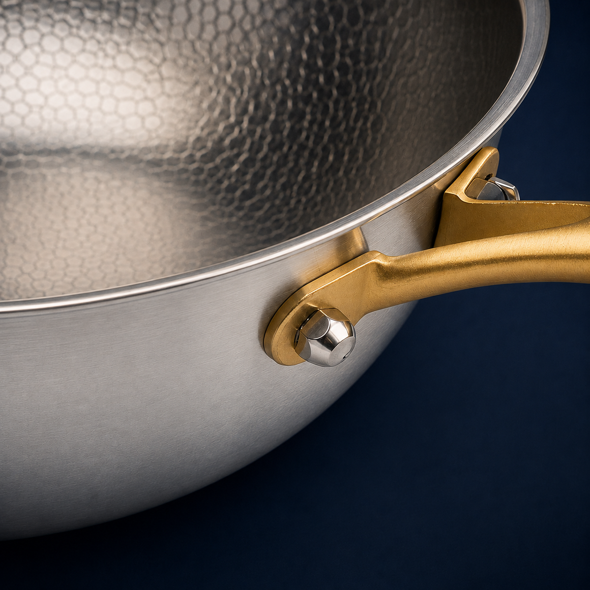 Détail du manche or et de la surface martelée d'un wok en titane Maison Ferré®