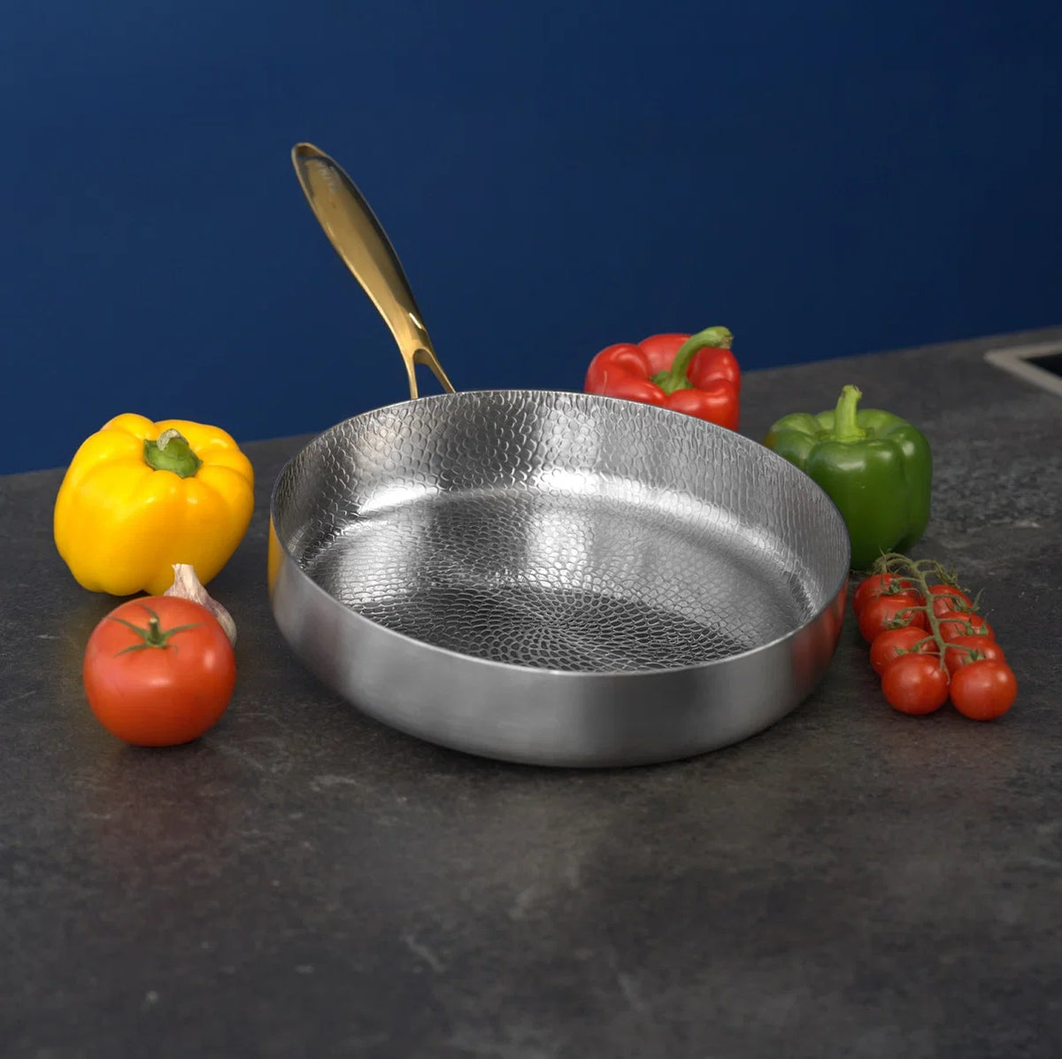 Poêle profonde en titane Maison Ferré® entourée de poivrons et de tomates fraîches